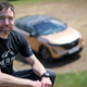 A photo of adventurer Chris Ramsay with a Nissan EV in the background.